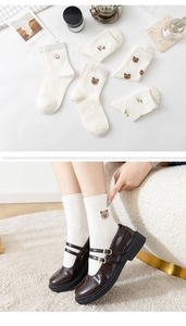 Detail of white cotton socks featuring cute bear embroidery and ribbed knit texture