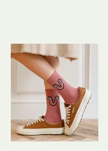 Detailed shot of pink crew socks featuring a cute cartoon smiley face and cotton fabric