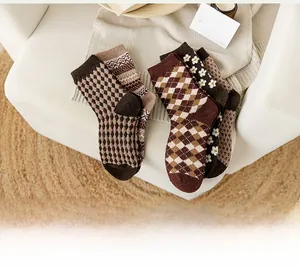 Vue à plat de chaussettes en laine rétro à carreaux et fleurs sur plaid douillet