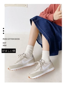 Detail view of off-white ribbed cotton socks paired with sneakers and denim skirt