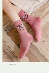 Detailed close-up of pink mid-calf socks with funny cartoon face embroidery on cotton fabric