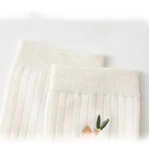 Detail of ribbed cuff and carrot embroidery on white cotton mid-calf socks