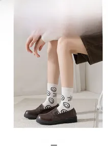 Gros plan de chaussettes en coton blanc avec smiley noir et slogan 'Have a nice day' brodé