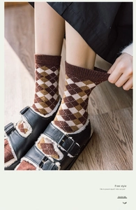 Détail de chaussettes en laine à motifs losanges avec des chaussures en cuir noir