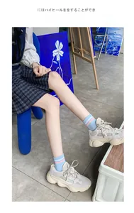 Dettagli di sneakers chunky beige abbinate a calze di cotone a righe azzurre