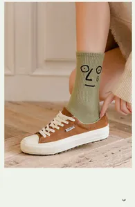 Close-up of funny cartoon expression face on green cotton socks with brown suede sneakers