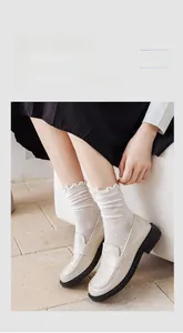 Close-up of cream cotton crew socks with lace trim paired with beige loafers