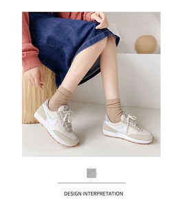Close-up of beige and grey sneakers with ribbed socks and a long denim skirt