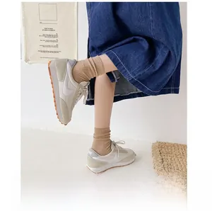 Close-up of beige retro sneakers featuring mesh suede texture and waffle rubber sole