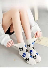 Detail of cream crew socks featuring blue and black heart patterns with ribbed cuffs