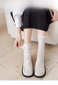 Close-up of white floral lace mesh socks with ruffled cuffs and breathable sheer texture