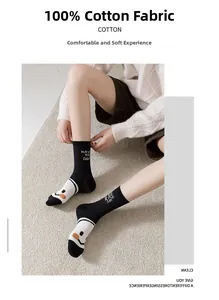 Détail de chaussettes en coton noir avec texte 'HAVE A NICE DAY' et motif smiley blanc