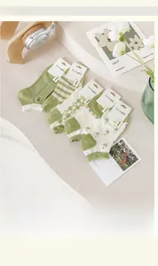 Close-up of five pairs of green floral combed cotton socks with lace trim and jacquard