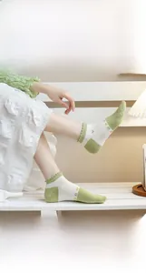 Close-up of green cotton crew socks with delicate flower embroidery and ruffled lace edges