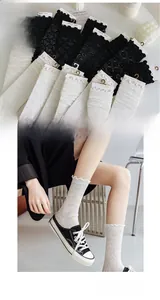 Detail of white and black lace socks with floral mesh texture and wavy ruffled edges