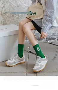 Close-up of bright green cotton socks with white letter C embroidery and ribbed texture