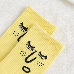 Bright yellow cotton crew socks featuring a cute cartoon face and ribbed knit texture
