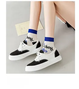 Detail of retro crew socks with blue artistic text paired with black and white canvas shoes