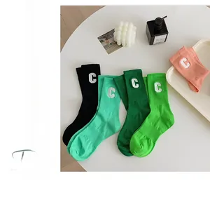 Flat lay of colorful cotton socks with C-letter embroidery on a minimalist white table