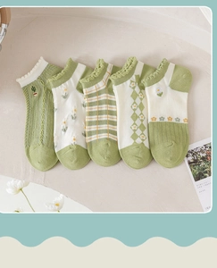 Detail of five pairs of green low-cut socks with floral patterns and ruffled cuffs