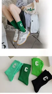 Detail view of cotton rib-knit socks with white C-letter embroidery in various green tones