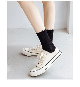 Detail of black lace mesh socks with hollow diamond pattern and wavy ruffled cuffs
