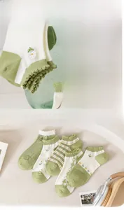 Detail of five pairs of floral green cotton socks with ruffled edges and embroidery