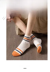 Detail of white cotton athletic socks featuring orange and blue stripes with logo embroidery