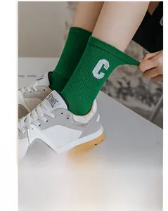 Detail of green ribbed cotton sock with embroidered white letter C and elastic fit