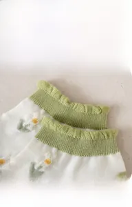 Detail of green floral striped sock with ruffled elastic cuff and daisy embroidery