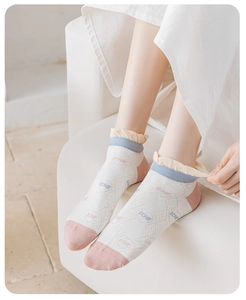 Close-up of women's white plaid ankle socks with ruffled edges and pink heart pattern