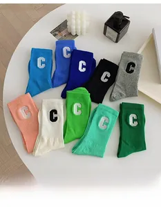 Macro detail of cotton crew socks showing ribbed knit texture and C letter embroidery