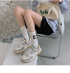 Detail of retro sneakers in white and grey suede paired with high cotton lettered socks