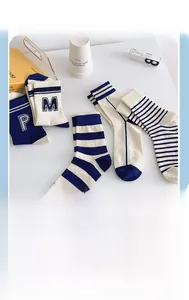 Close-up of three pairs of navy blue and off-white striped cotton socks in retro prep style