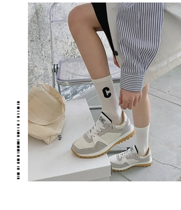 Close-up of crew socks featuring black 'C' letter embroidery and retro sneakers