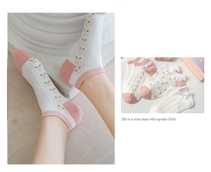 Detail of white cotton socks with pink floral embroidery and delicate openwork texture