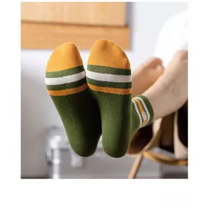Close-up of green cotton crew socks with orange stripes and heel detail for men