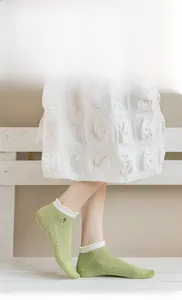 Detail of light green low cut sock with white ruffled trim and delicate embroidery