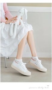 Detail of white canvas low-top sneakers with textured rubber sole and strawberry socks