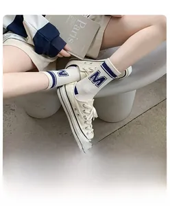 Detailed view of white ribbed mid-tube socks with blue stripes and M embroidery
