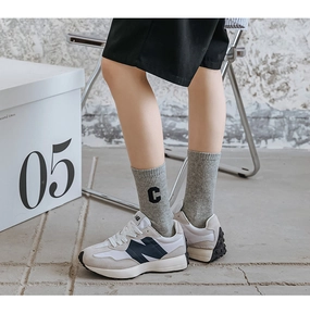Close-up of ribbed cotton socks with letter C embroidery paired with vintage sneakers