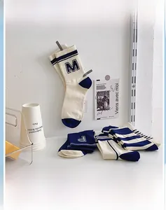 Detail view of college style mid-tube socks with varsity letter M P embroidery and stripes