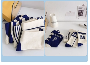 Detail of blue and beige cotton crew socks featuring striped patterns and letter embroidery