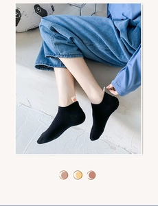 Close-up of black low cut socks featuring a red heart label on the heel with denim jeans