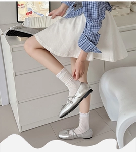 Detail of white ruffled lace crew socks paired with silver Mary Jane bow ballet flats