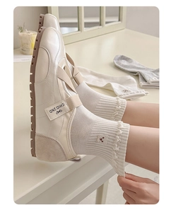 Close-up of cute bear embroidery on frilled white crew socks with vintage Mary Jane shoes
