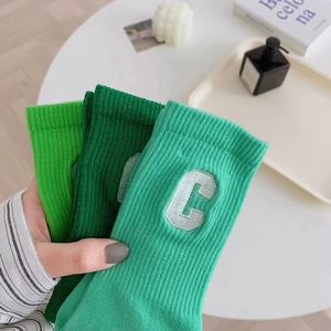 Three pairs of green cotton crew socks with white embroidered C letter on ribbed cuffs