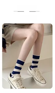 Blue and white striped mid-tube socks styled with off-white canvas shoes on steps