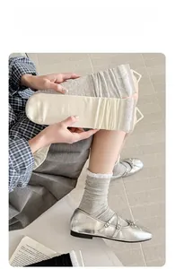 Detail of ballet style ruffled socks in grey and off-white with cotton rib texture