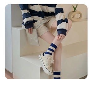 Detail of blue and white striped crew socks paired with canvas shoes in a cozy setting
